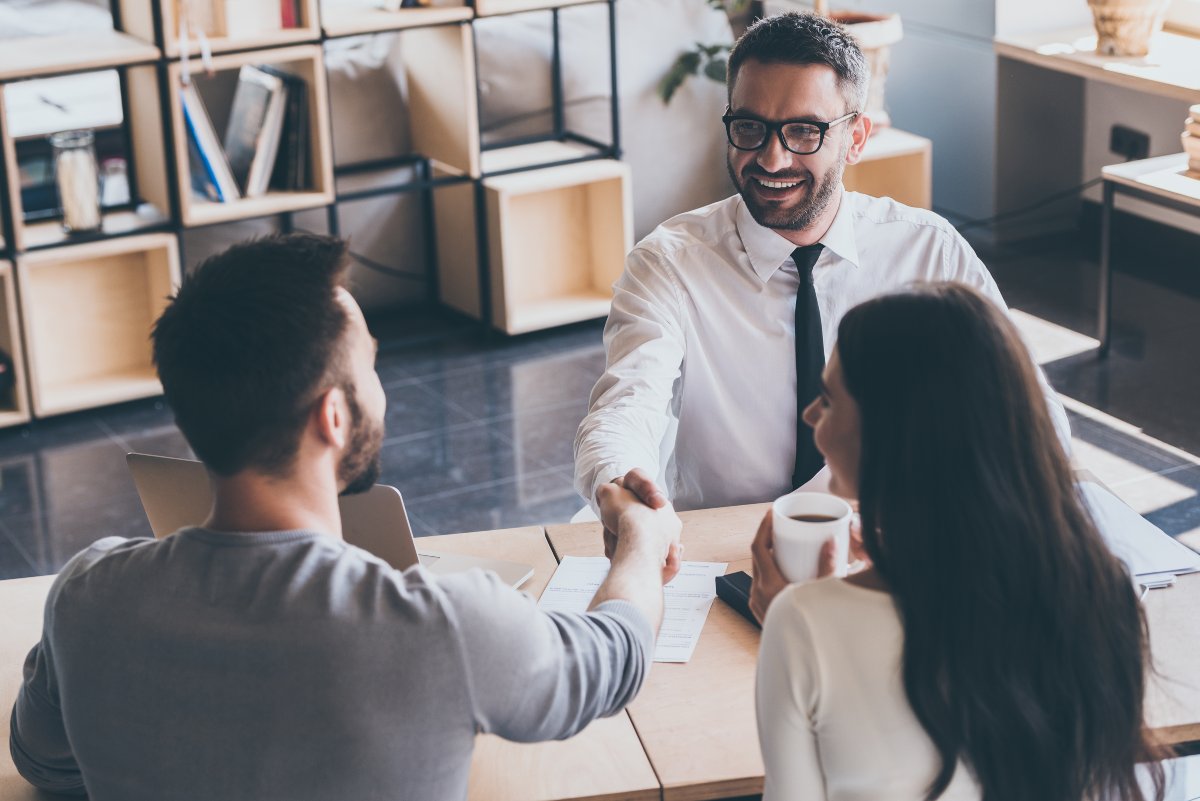 Young couple meeting and shaking hands with real estate agent.