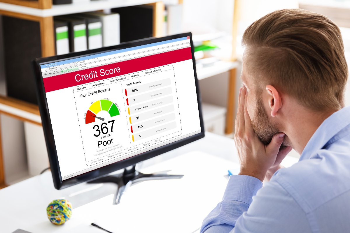 Upset individual looking at bad credit score on computer.