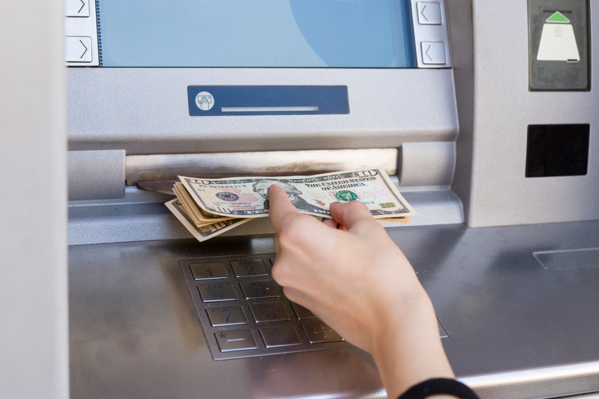 Close up on hand withdrawing cash from ATM.