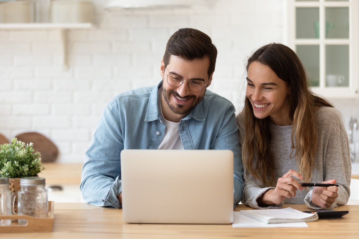 Smiling couple on computer calculating finances.