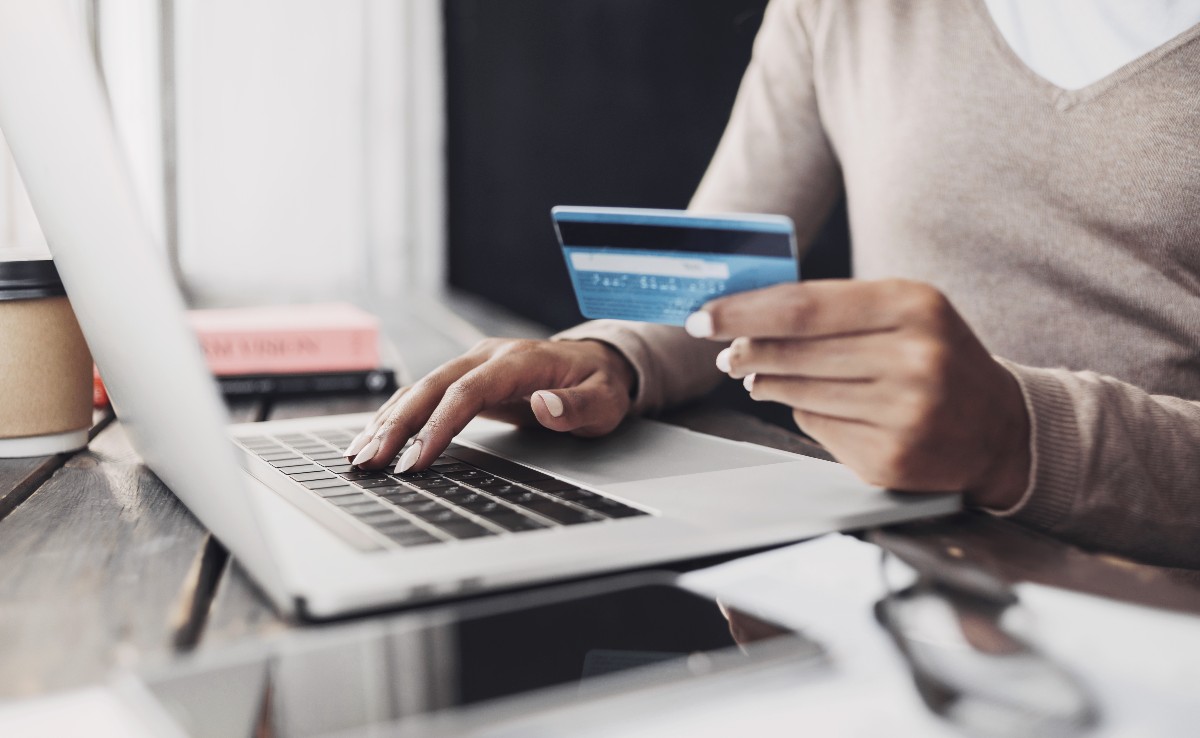 Close up of hand holding credit card and typing on laptop.