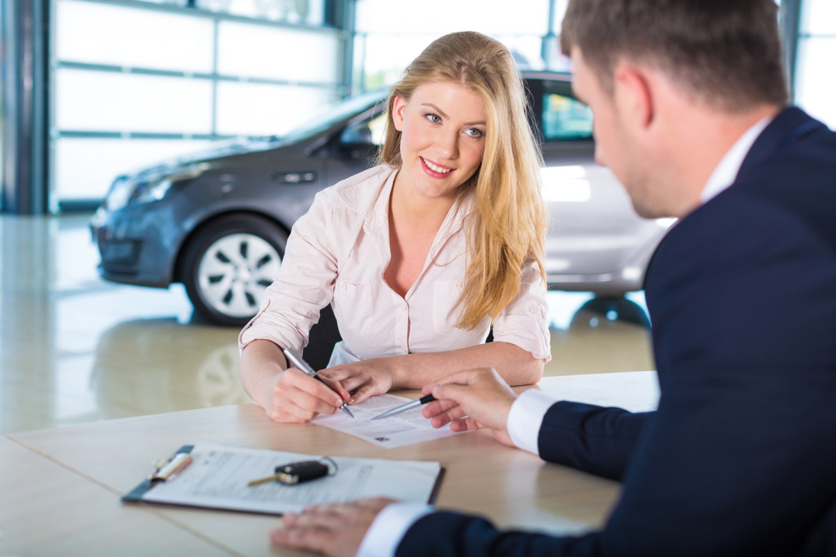 Woman signs car paperwork.