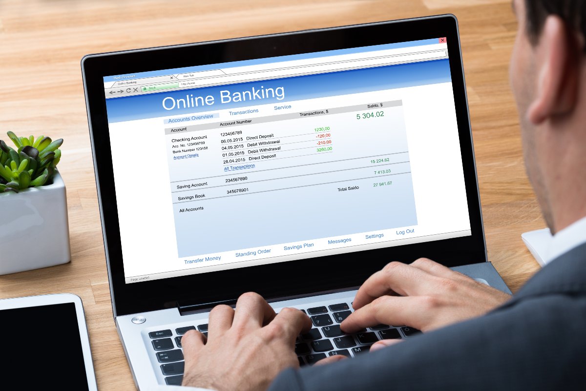 Individual checking online banking account on laptop.