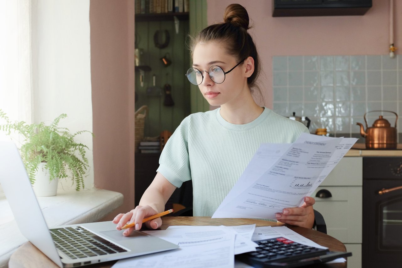 Young adult calculating finances on laptop.