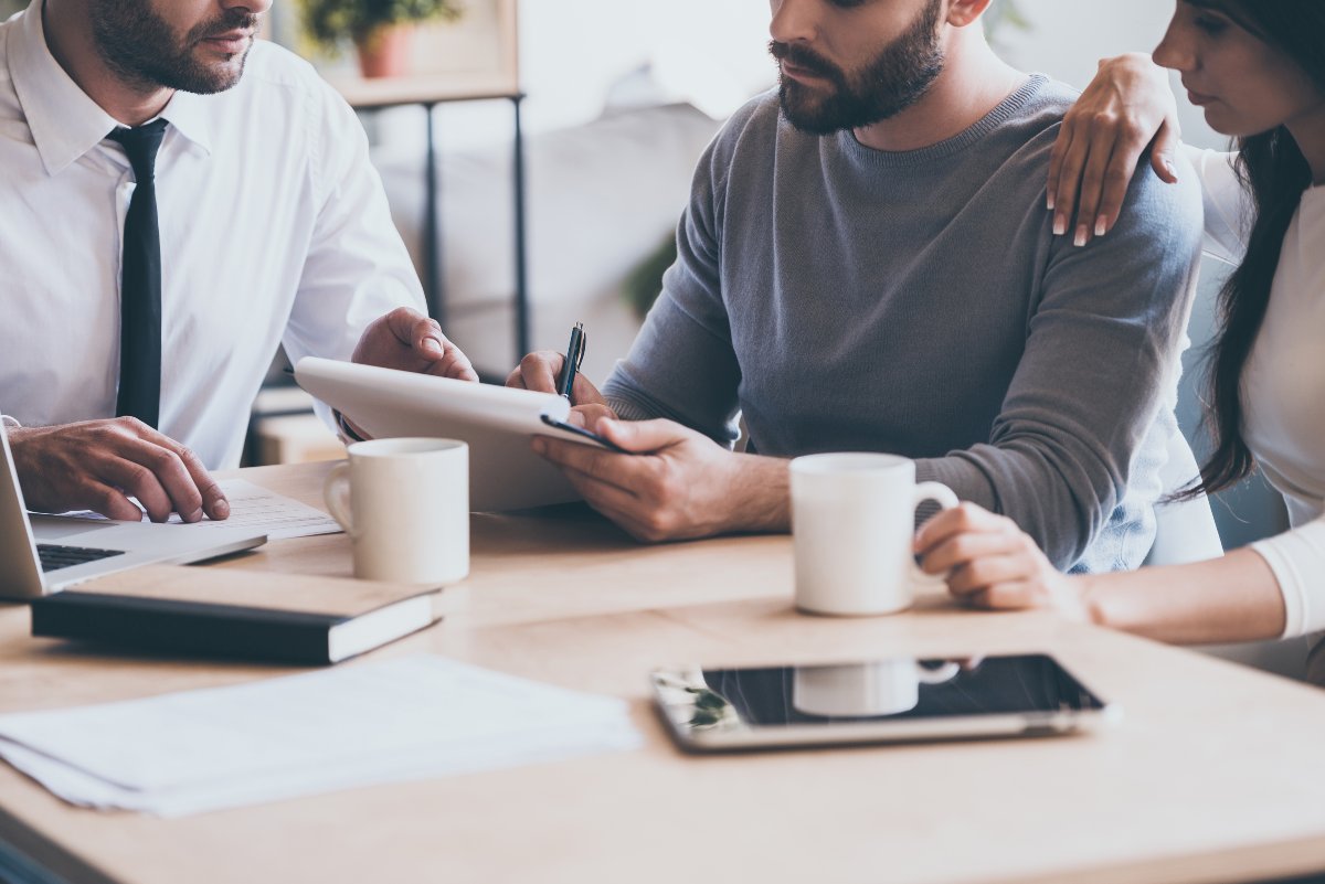 Couple signing real estate paperwork with agent.